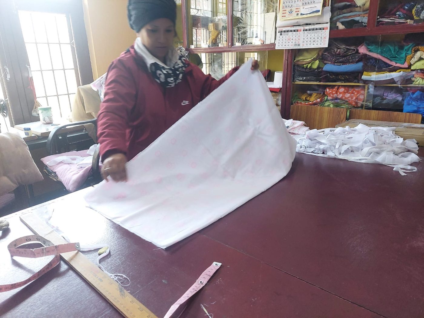 An artisan lifting a length of hand-printed rose cotton in the Nepal workshop
