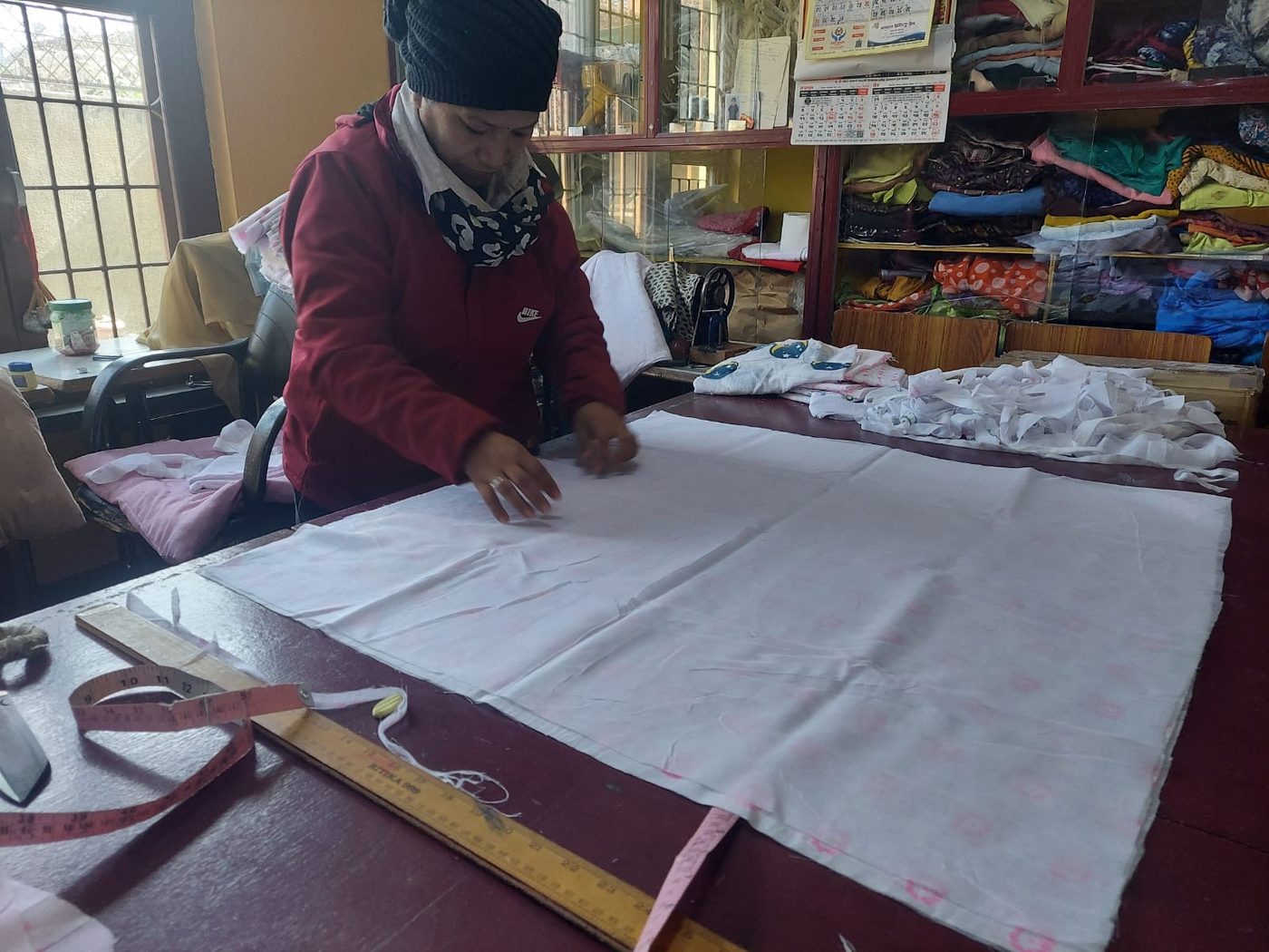 An artisan smoothing hand-printed cotton across the cutting table in the Primula workshop in Nepal